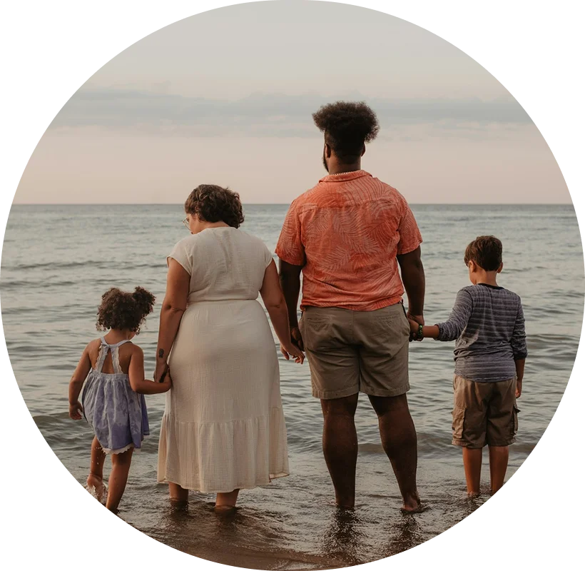 a family holding hands standing on the shoreline of the ocean